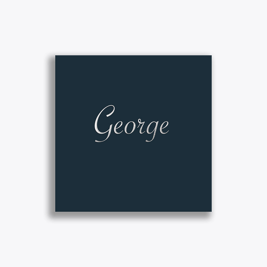 Het geboortekaartje voor George is gedrukt op cobaltblauw papier. De naam is geschreven in een sierlijk lettertype en als druktechniek is gekozen voor diepdruk in combinatie met zilverfolie.