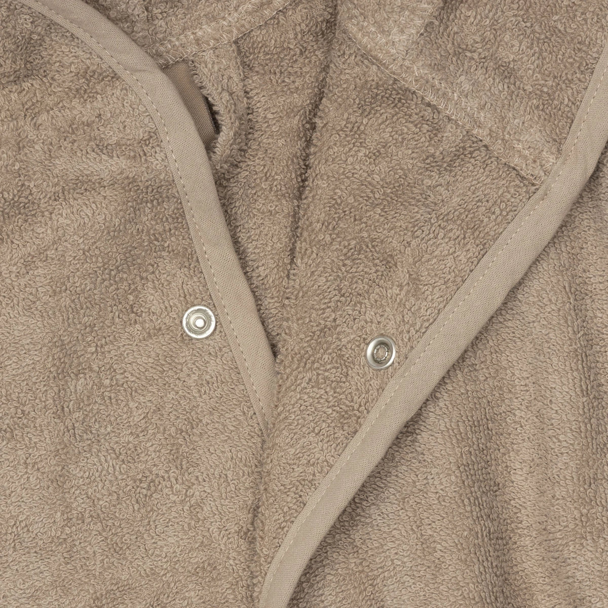 Detail van de drukknopen en de zachte badstof van de Jollein badjas Milky Coffee